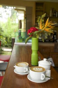 a table with two cups of coffee and a vase with flowers at Olive Gardens Hotel Kampala in Kampala