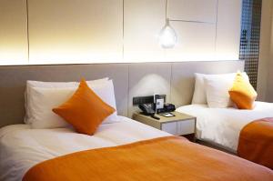 a hotel room with two beds with orange and white pillows at The QUBE Hotel Ningbo North in Ningbo