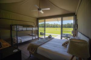 a bedroom with a bed with a fan and a window at Habitat Noosa in Cootharaba