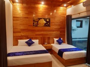 two beds in a room with wooden walls at Trang an green river homestay in Ninh Binh
