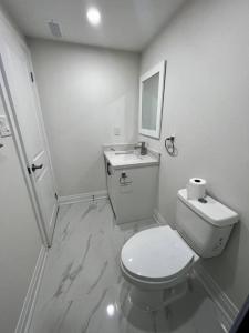 a white bathroom with a toilet and a sink at New Luxurious Studio Apartment in Brampton