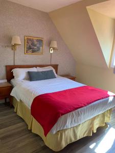 1 dormitorio con 1 cama grande con manta roja en Hotel Cowansville, en Cowansville