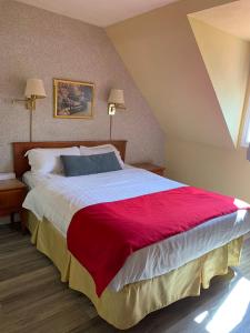 a bedroom with a large bed with a red blanket at Hotel Cowansville in Cowansville
