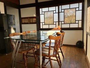 comedor con mesa de cristal y sillas en お宿でん吉, en Minami Aso