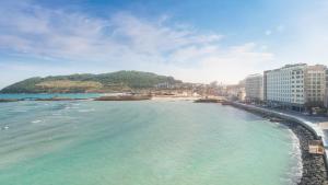 a view of a beach with buildings and the ocean at Gloucester Hotel Hamdeok in Jeju