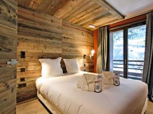 a bedroom with a wooden accent wall with a bed at Appartement skis aux pieds avec concierge 5* à Méribel - FR-1-613-38 in Méribel