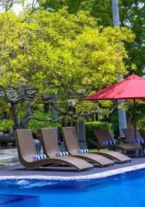 - un groupe de chaises et un parasol à côté de la piscine dans l'établissement Chaarya Resort & Spa, à Tissamaharama