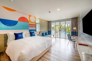 a hotel room with a large bed and a television at NH Boat Lagoon Phuket Resort in Phuket
