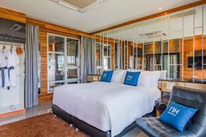 a bedroom with a large white bed and a chair at NH Boat Lagoon Phuket Resort in Phuket Town