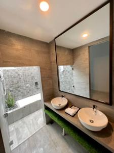 a bathroom with two sinks and a large mirror at Chantara Cottage in Kampung Mawar