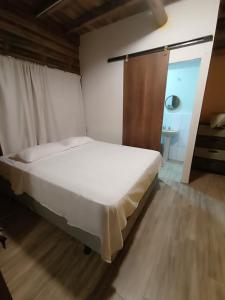 1 dormitorio con cama blanca y suelo de madera en Hostal Fara en Jama