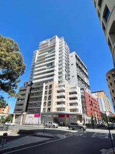 a tall white building with cars parked in front of it at Charming One-Bed Apt in the Heart of Parramatta in Sydney