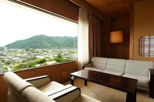 Isawa Tokiwa Hotel في Fuefuki: غرفة معيشة مع أريكة ونافذة كبيرة