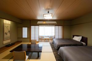 ein Hotelzimmer mit 2 Betten und einem Tisch in der Unterkunft Isawa Tokiwa Hotel in Fuefuki