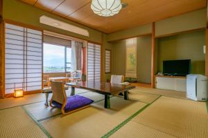 Isawa Tokiwa Hotel في Fuefuki: غرفة معيشة مع طاولة وكراسي وتلفزيون