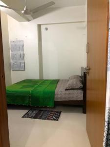 ein Schlafzimmer mit einem Bett mit einer grünen Decke in der Unterkunft Home Away From Home in Chittagong