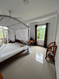 a bedroom with a bed and a chair and a window at Minara Guest House in Mirissa