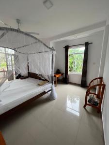 1 dormitorio con 1 cama, 1 silla y 1 ventana en Minara Guest House, en Mirissa