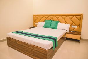 a bedroom with a bed with green and white pillows at Hotel Green Apple in Rourkela