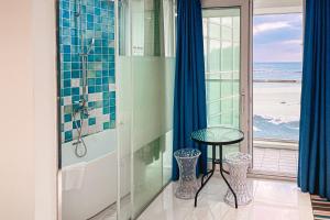 a bathroom with a shower with a table and a window at Hamdeok Beach Stay Jeju in Jeju