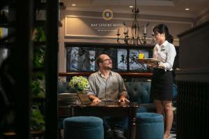 a woman standing next to a man at a table at Maya boutique Hotel HN - by BAY LUXURY in Hanoi