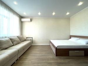 a bedroom with a bed and a couch and a window at Новостройка с красивым видом 9 этаж in Petropavlovsk