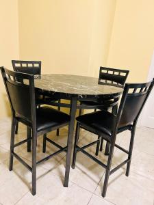 a black table with four chairs and a marble top at The Rest Stop-B- 15 min from Airport/24hrs Security in Montego Bay