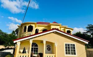 una casa amarilla con techo rojo en The Rest Stop-B- 15 min from Airport/24hrs Security en Montego Bay