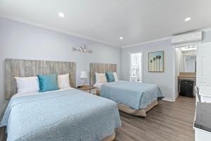 two beds in a bedroom with blue and white at Ocean Lodge Santa Monica Beach Hotel in Los Angeles