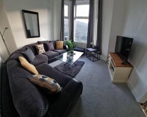 a living room with a couch and a television at Modern 4-Bedroom Townhouse With Private Garden in Abertillery