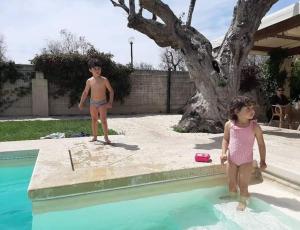 un niño y una niña parados junto a una piscina en Casasalento en Cavallino di Lecce