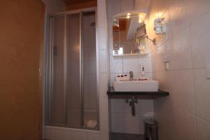 a white bathroom with a sink and a shower at Gästehaus Alpina in Sankt Anton am Arlberg