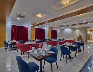 un restaurante con mesas, sillas y cortinas rojas en Golden Tulip Tirupati, en Tirupati