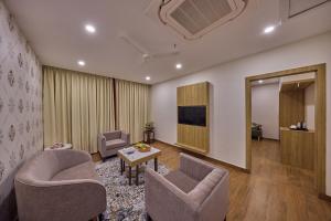 a living room with two chairs and a television at Golden Tulip Tirupati in Tirupati