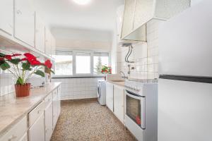 a white kitchen with white appliances and red plants at Happy Holiday Cascais - Home in Cascais