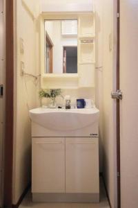 a bathroom with a white sink and a mirror at Osaka MISAKI Traditional Japanese house 2-6 ppl near station in Osaka