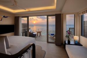 een slaapkamer met een bed en uitzicht op de oceaan bij Avani+ Fares Maldives Resort in Baa Atoll