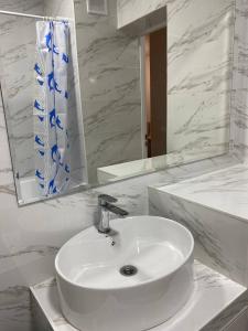 lavabo blanco en el baño con espejo en Уютная квартира-студия ЖК Теремки en Almaty