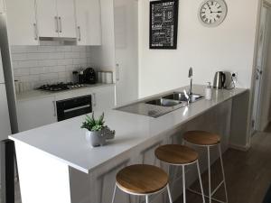 a kitchen with a counter with stools and a sink at Discover Warilla - Bright and Airy Townhouse near the Beach and Lake in Lake Illawarra
