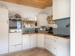 a kitchen with white cabinets and wooden floors at Chalet in Rangersdorf in Carinthia near ski area in Rangersdorf