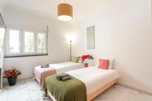 two beds in a room with white walls and windows at Happy Holiday Cascais - Home in Cascais