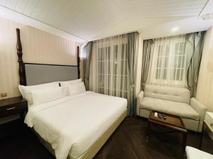 ein Schlafzimmer mit einem weißen Bett und einem Stuhl in der Unterkunft Grand Florida Beachfront Pattaya H502 in Na Jomtien