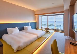 a hotel room with a bed and a view of the ocean at HOTEL AlaCOOJU OKINAWA in Minatogawa