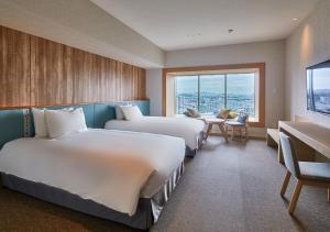 ein Hotelzimmer mit 2 Betten und einem großen Fenster in der Unterkunft HOTEL AlaCOOJU OKINAWA in Minatogawa