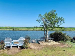 two white chairs and a table next to a lake at A unique, off-grid Eco Friendly Beach House. in Wolferton