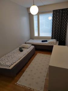 two beds in a room with a window at Spacious super located Lahti apartment in Lahti