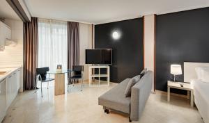 マドリードにあるSercotel Togumarのベッド、ソファ、テレビが備わるホテルルームです。