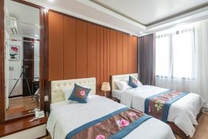 a hotel room with two beds and a mirror at Hương Nam Hotel in Ha Long