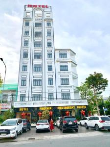duży biały budynek z samochodami zaparkowanymi przed nim w obiekcie Phụng Hoàng Vũ w mieście Bạc Liêu
