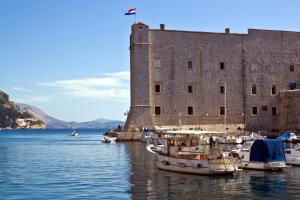 un groupe de bateaux dans l'eau devant un château dans l'établissement Apartment NAVA - new and spacious gem in the port, à Dubrovnik